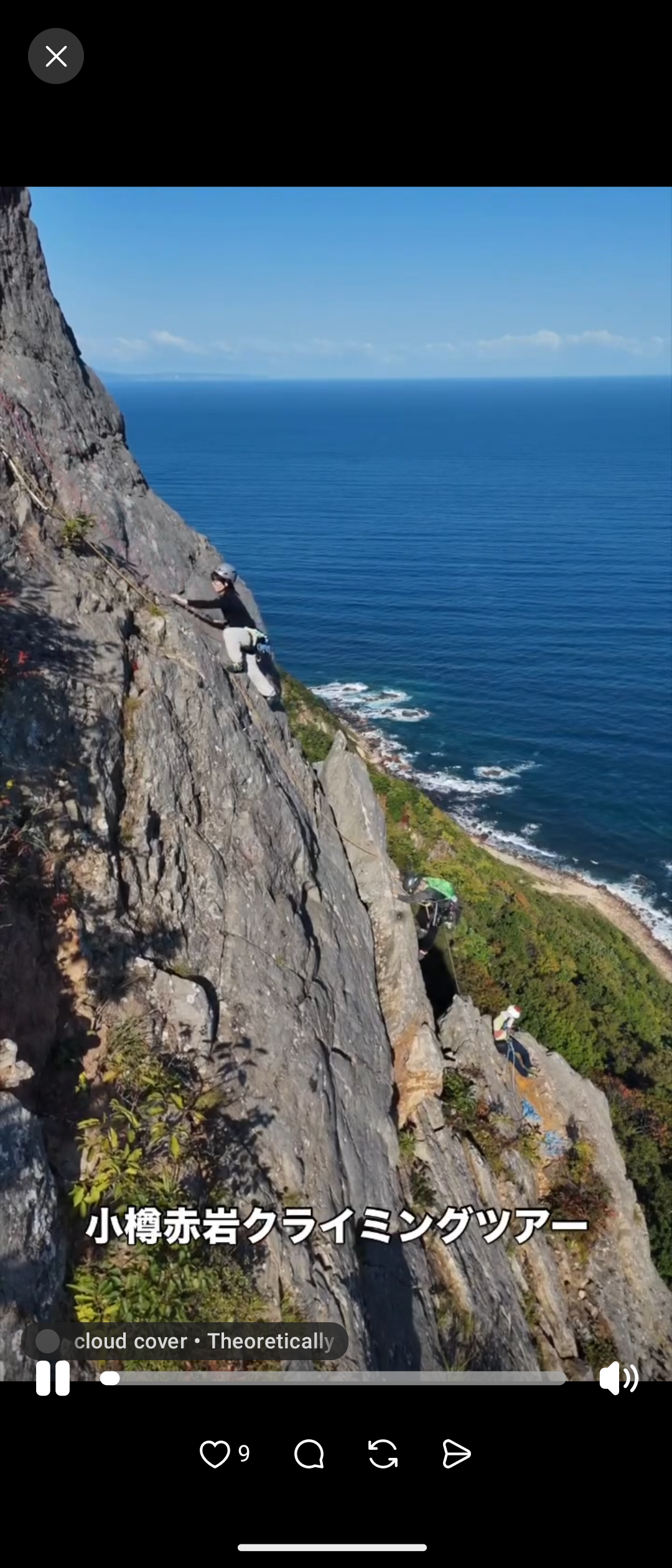A climber wearing a helmet on the rock face, with the sea behind.